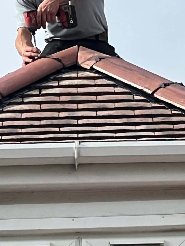 This is a photo of one of the operatives of Histon Roofing Repairs installing new ridge tiles